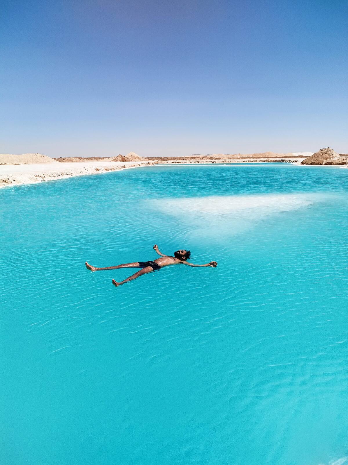Мъж, който плава по гръб в оазис Сива в Египет