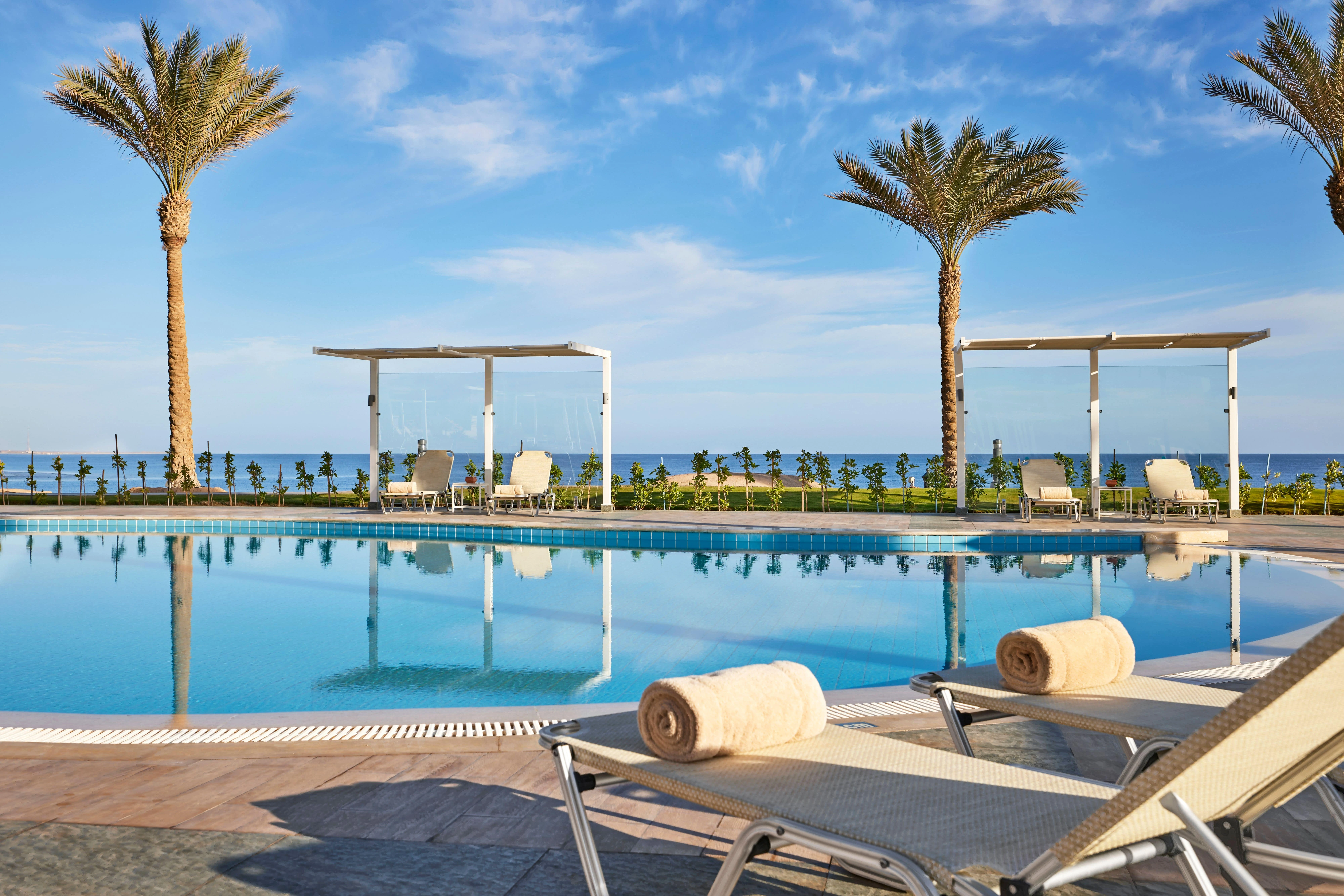 Басейн с палми и шезлонги в JAZ Samaya хотел в Марса Алам, Египет